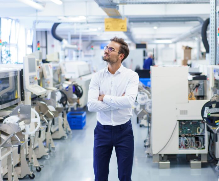 Thoughtful,Young,Businessman,Standing,With,Arms,Crossed,While,Looking,Away